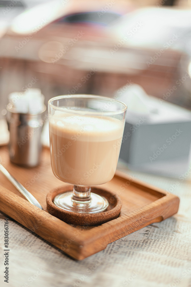 Hot raf coffee in a glass stylish cup on a wooden board in a street cafe on a park background. Morning coffee on the terrace in cafe Hot raf coffee in a glass stylish cup on a wooden board in a street cafe on a park background. Morning coffee on the terrace in cafe
