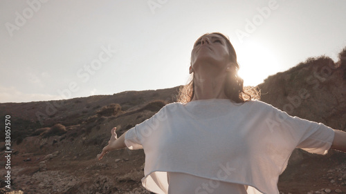 Young woman with outstretched hands doing yoga in early morning on the beach. High quality photo photo