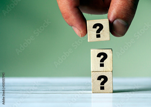 Three question mark sign on wooden block. Stack of question mark. Hand put b block on stack, quiz