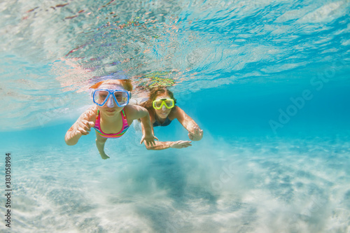 Valokuva Young mother with child in snorkeling mask dive in coral reef sea lagoon to explore underwater world