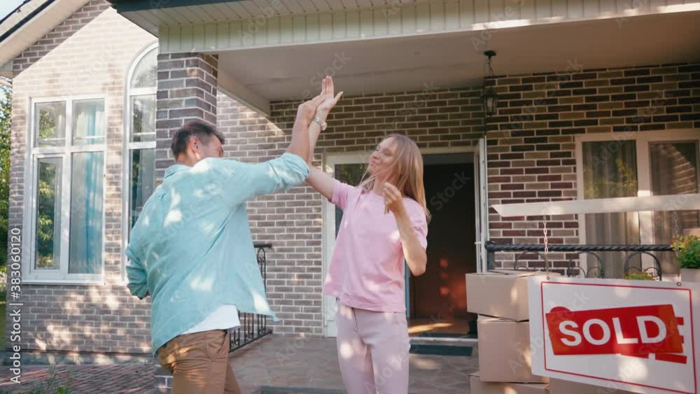 man giving keys to joyful wife jumping near new house