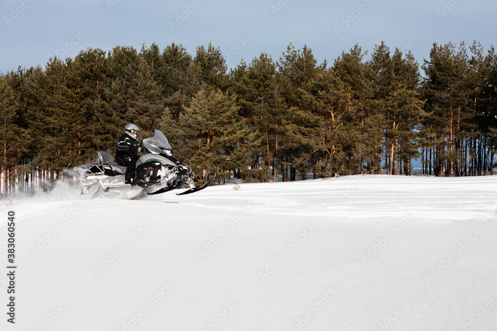 In deep snowdrift snowmobile rider driving fast. Riding with fun in white snow powder during backcountry tour. Extreme sport adventure, outdoor activity during winter holiday on ski mountain resort. In deep snowdrift snowmobile rider driving fast. Riding with fun in white snow powder during backcountry tour. Extreme sport adventure, outdoor activity during winter holiday on ski mountain resort.