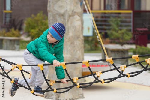 A nimble boy climbs a rope ladder in a hanging city on a playground.