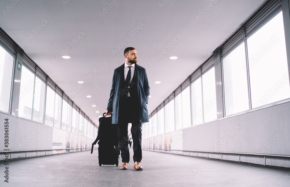 Fototapeta premium Pensive man in suit walking along airport hallway