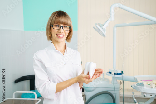 Portrait of happy woman dentist on the background of dental office holding tool