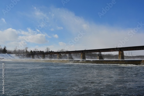 Winter scenery along the Grand River with view of the railroad bridge in Caledonia, Ontario Canada © skyf