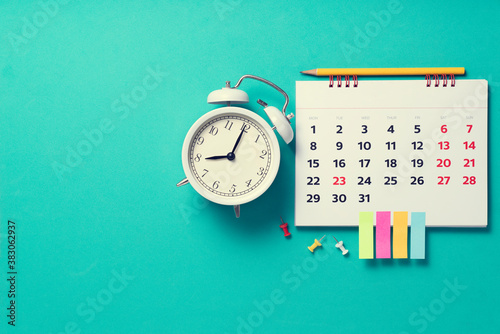 close up of calendar and alarm clock on the green table background, planning for business meeting or travel planning concept