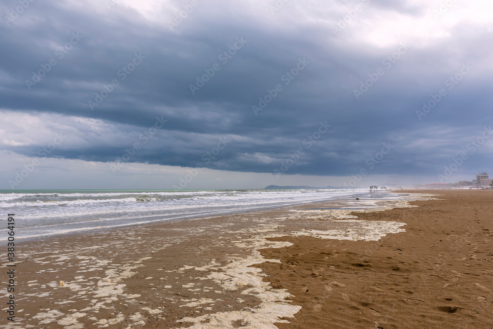 The long and wide beach of Rimini, Emilia Romagna, Italy, under a dramatic sky in the winter season