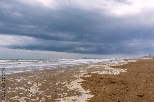 The long and wide beach of Rimini, Emilia Romagna, Italy, under a dramatic sky in the winter season photo