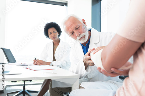 Assistant with doctor checking arm injury of patient © focusandblur