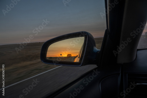 Dawn view in the side mirror of a car.