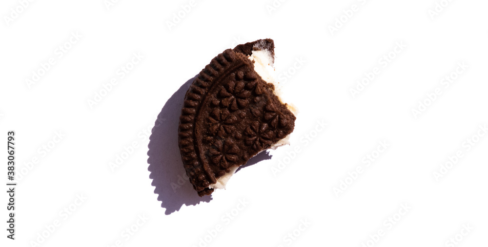 Take a bite of the cookie, which consists of two parts and a cream layer in the middle. Chocolate crumbly cookies on a white background. Isolate one - third of the dark chocolate cookies. Take a bite of the cookie, which consists of two parts and a cream layer in the middle. Chocolate crumbly cookies on a white background. Isolate one - third of the dark chocolate cookies.