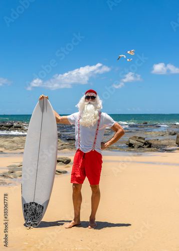 Canvas Print Santa Claus with a surf board with the ocean on backgraund