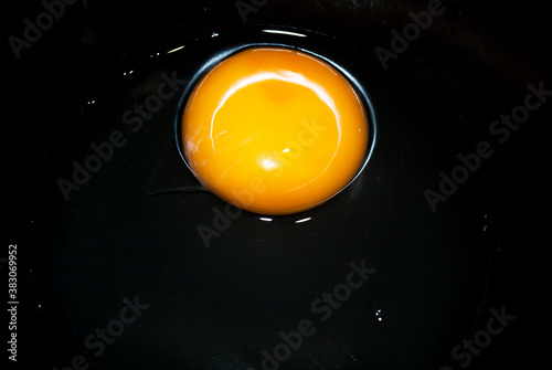 Broken raw egg in a black / dark gray plate. Cooking concept.