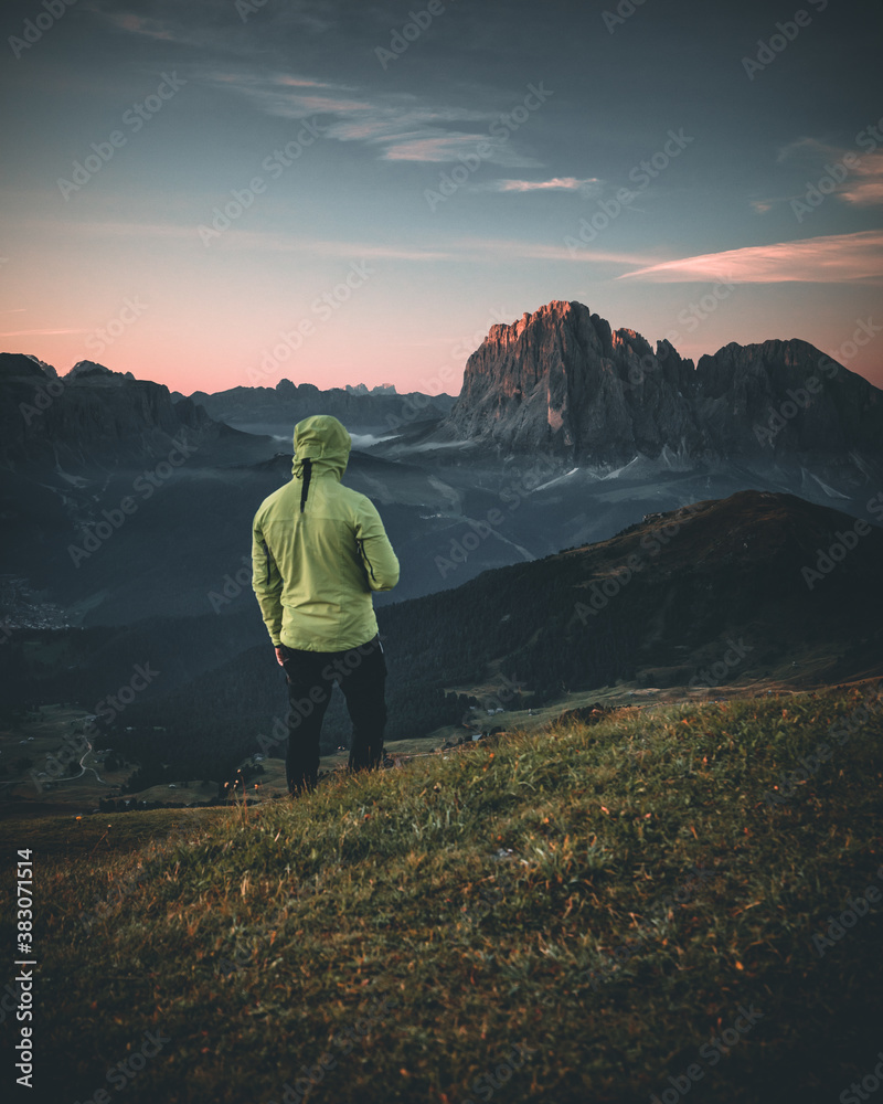 man standing on mountain peak in dolomites during sunrise