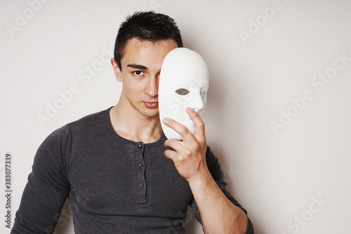 Cuadro en lienzo young man taking off white mask revealing face and identity - with copy space