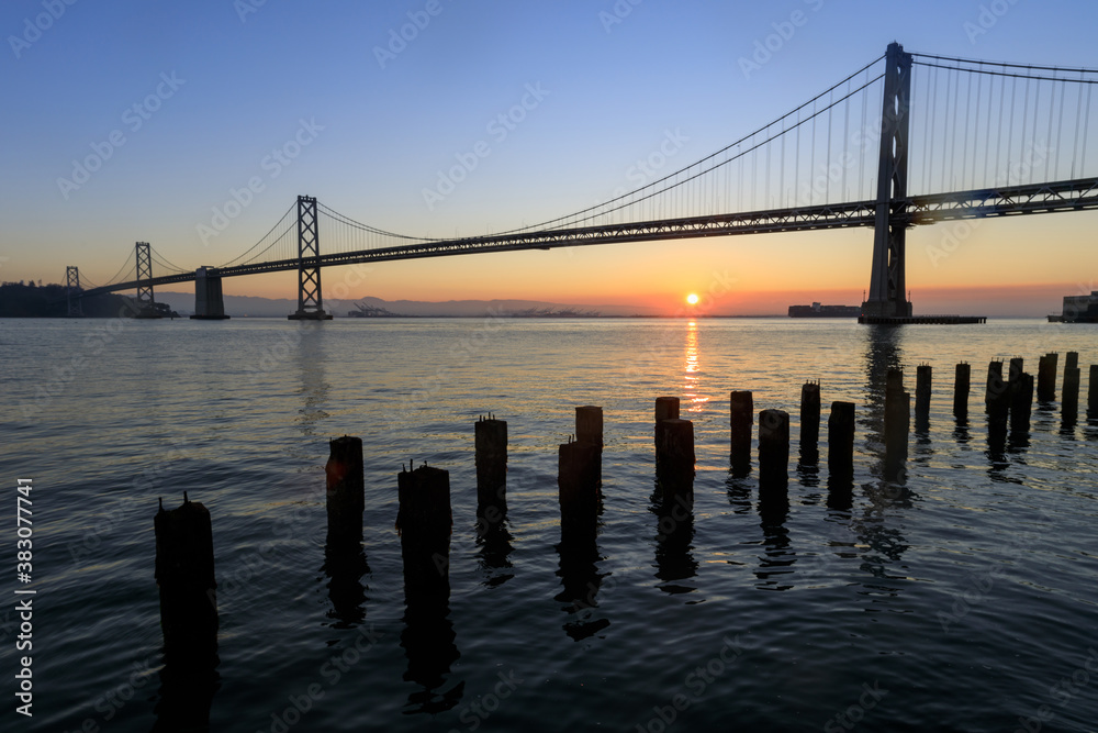 Sun rising behind Bay Bridge via The Embarcadero of San Francisco. Sun rising behind Bay Bridge via The Embarcadero of San Francisco.
