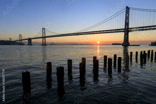 Sun rising behind Bay Bridge via The Embarcadero of San Francisco.