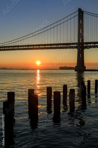 Sun rising behind Bay Bridge via The Embarcadero of San Francisco. © Yuval Helfman