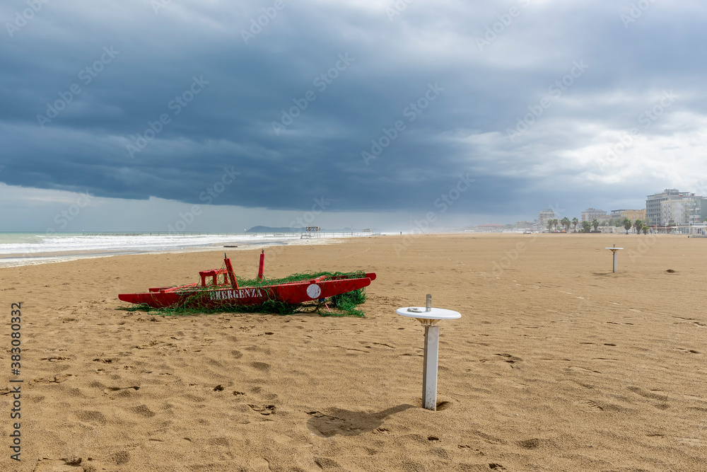 Fototapeta premium A typical red wooden rescue boat on the beach of Rimini, Italy, during a winter storm
