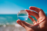A photo of the ocean through a circular crystal ball turning the picture in the ball upside down. The picture in the ball is in focus and the background is out of focus.