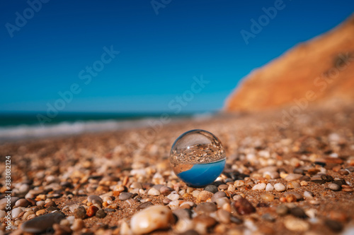 Beach with sea photographed through a crystal ball. The picture in the ball is in focus and the background is out of focus.