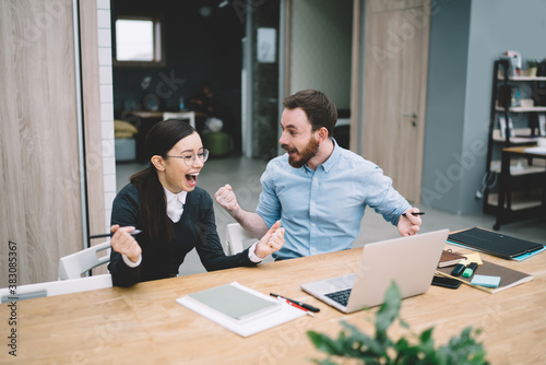 Excited man raising hands near woman screaming with joy