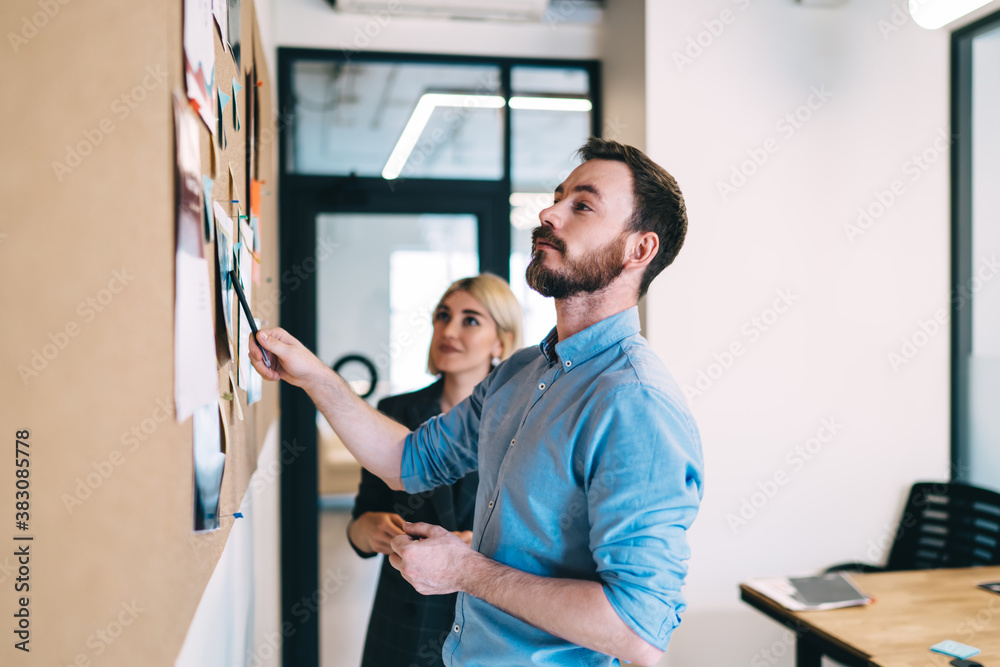 Satisfied businessman working with partner near cork board Satisfied businessman working with partner near cork board