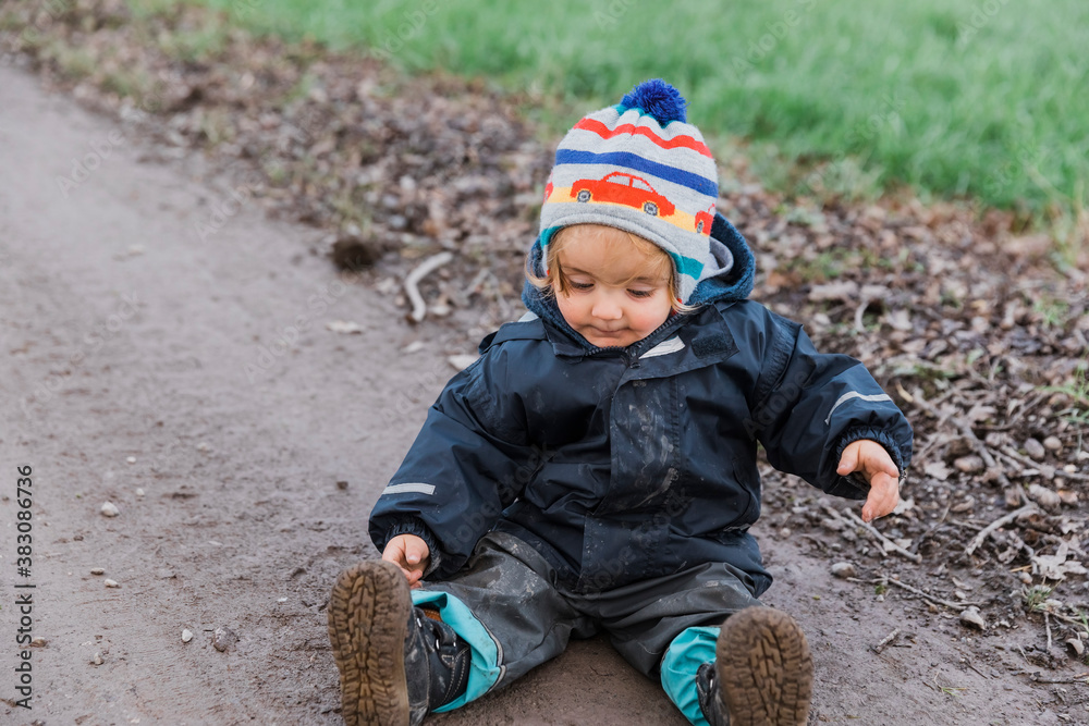 Toddler girl sitting with muddy pants on dirt road Toddler girl sitting with muddy pants on dirt road