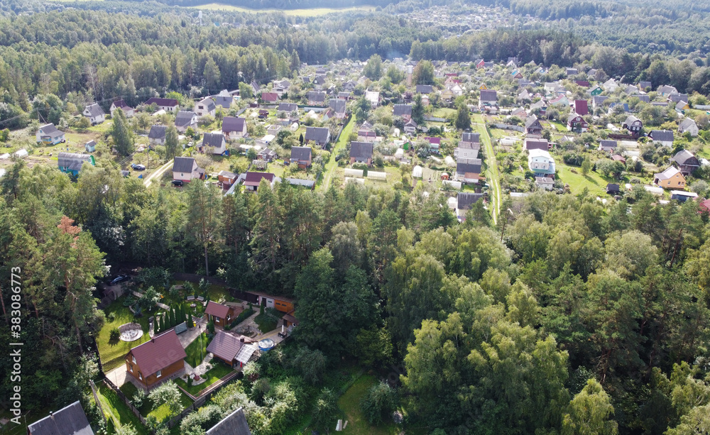 Obraz premium Beautiful top view of suburban cottages with park and forest. Rural landscape with roofs of small houses and villages