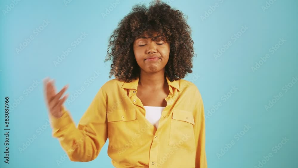 Dark-skinned woman taking a deep breath, rolling her eyes and showing fed up hand gesture posing on blue background