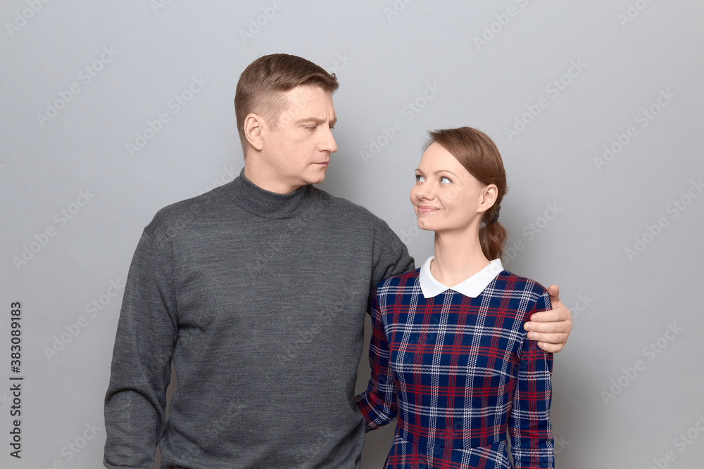 Portrait of serious man and joyful woman hugging and looking at each other Portrait of serious man and joyful woman hugging and looking at each other