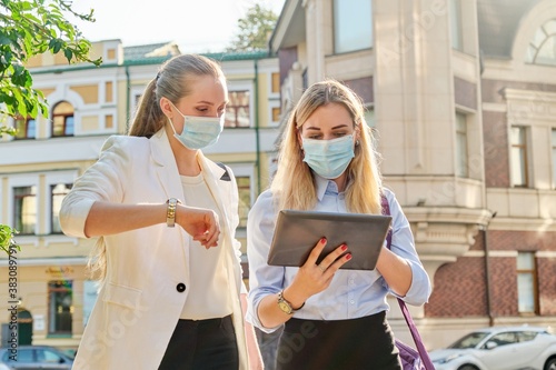 Business women wearing medical protective masks with digital tablet