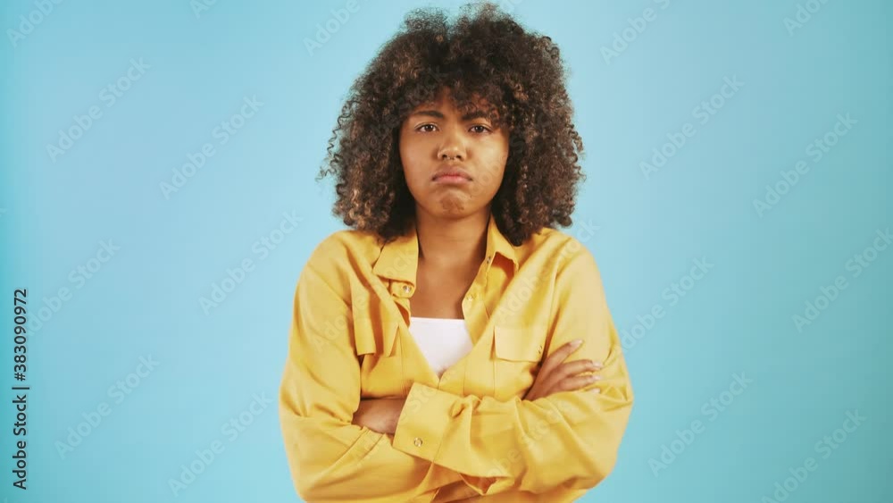 African-american lady looking sad and offended, folding hands on chest while posing against blue background African-american lady looking sad and offended, folding hands on chest while posing against blue background