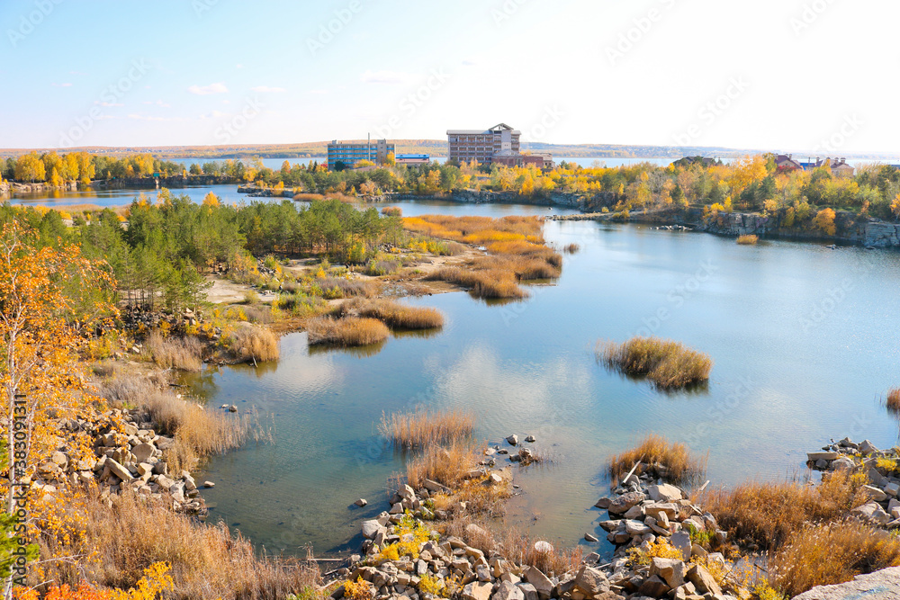 Beautiful old granite quarry with clear water in Indian summer. On the back is the Shershni reservoir. Chelyabinsk, Russia.