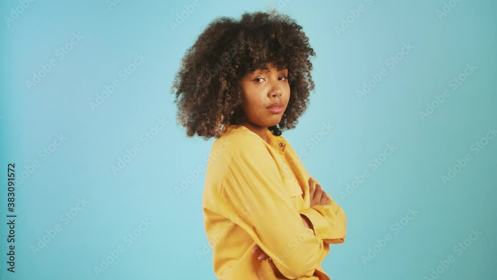 African-american woman rolling eyes being disappointed or annoyed while posing sideways against blue background African-american woman rolling eyes being disappointed or annoyed while posing sideways against blue background