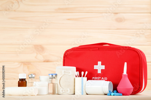 First aid kit with medical supplies on brown wooden table