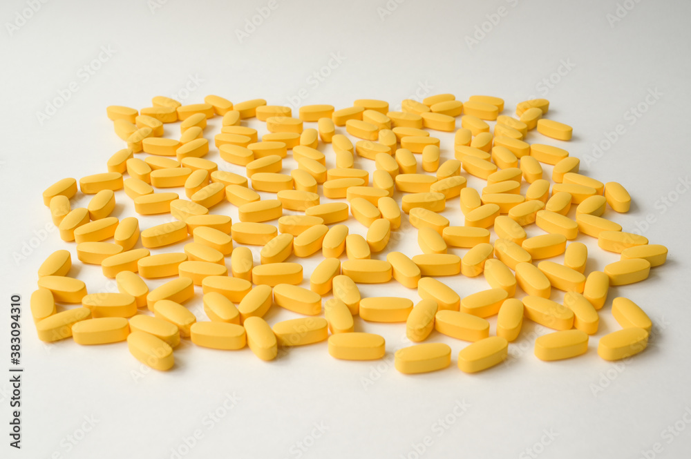Fototapeta premium pharmacy concept of handful of yellow tablets lying on a white surface