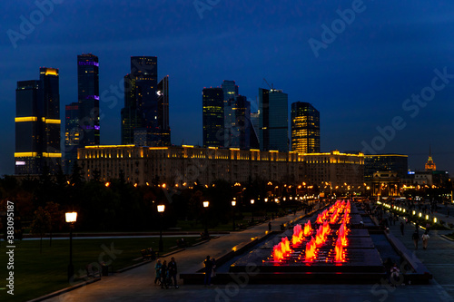 Evening and night views of the Moscow City skyscrapers through the glowing red fountains of Victory Park in Moscow. Lights of the night city.