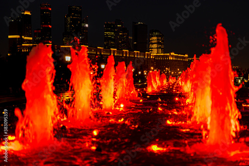 Evening and night views of the Moscow City skyscrapers through the glowing red fountains of Victory Park in Moscow. Lights of the night city.