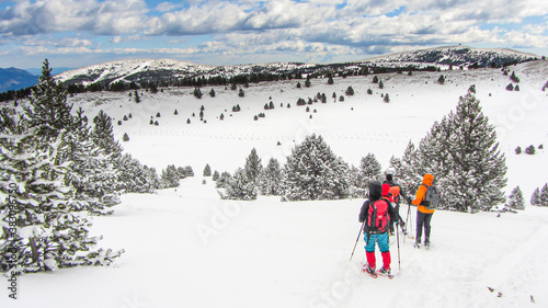 People walking in a snow landscape with snowshoes and backpacks in the Pyrenees. Hiking and skiing in winter.