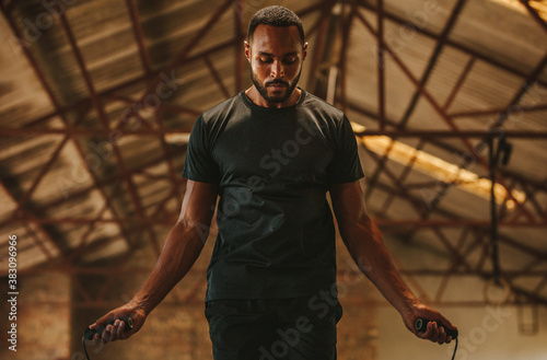 Fitness man skipping ropes at cross workout space photo