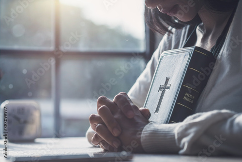 Christian girl holding hands with Bible to pray for blessings from God by faith.
