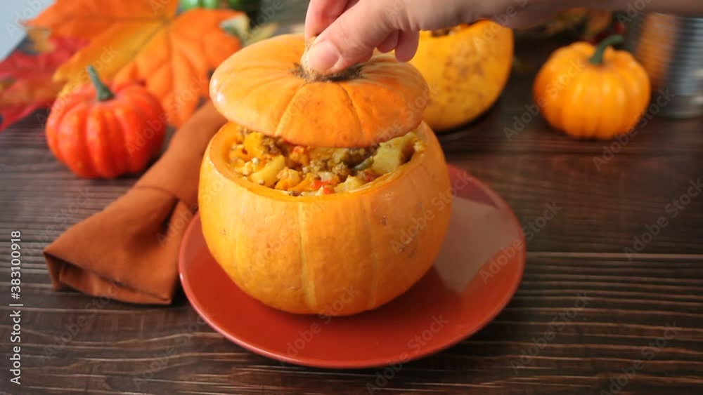 Fresh cooked pumpkin soup served in a pumpkin. Stuffed pumpkin. Woman hand opens the lid. Autumn warm and cozy food Fresh cooked pumpkin soup served in a pumpkin. Stuffed pumpkin. Woman hand opens the lid. Autumn warm and cozy food