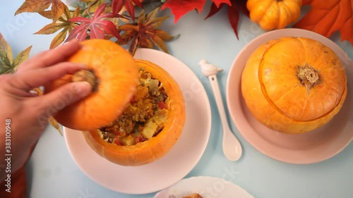 Fresh cooked pumpkin soup served in a pumpkin. Stuffed pumpkin. Woman hand opens the lid. Autumn warm and cozy food