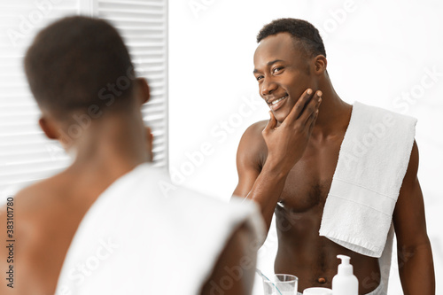 Black Guy Touching Well-Shaved Face Standing Shirtless In Modern Bathroom photo