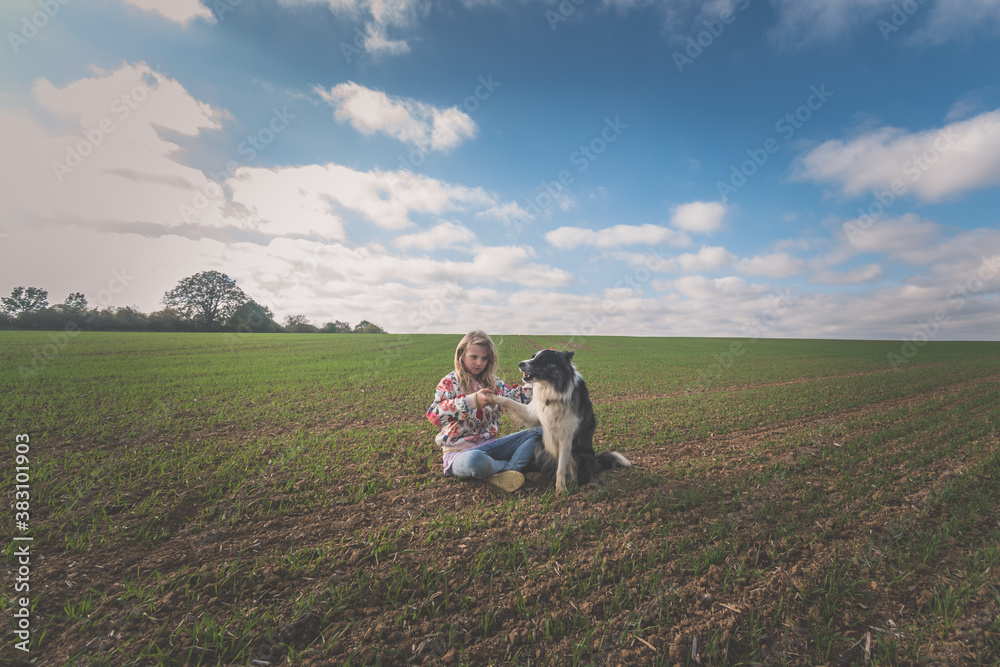 child and dog playing and hugging together in scenic field