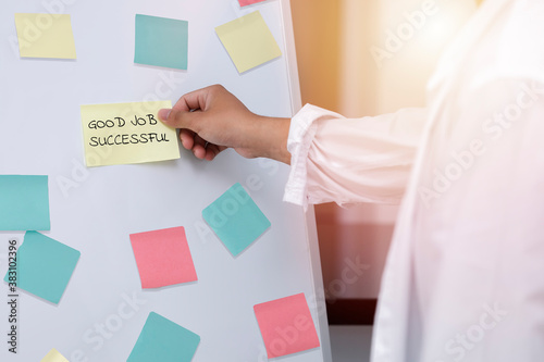 Close up mn hand taking  yellow sticky note on the whiteboard. Reminder planning and brainstorm ideas of the business,. business man hand hold post it. note with GOOD JOB SUCCESSFUL