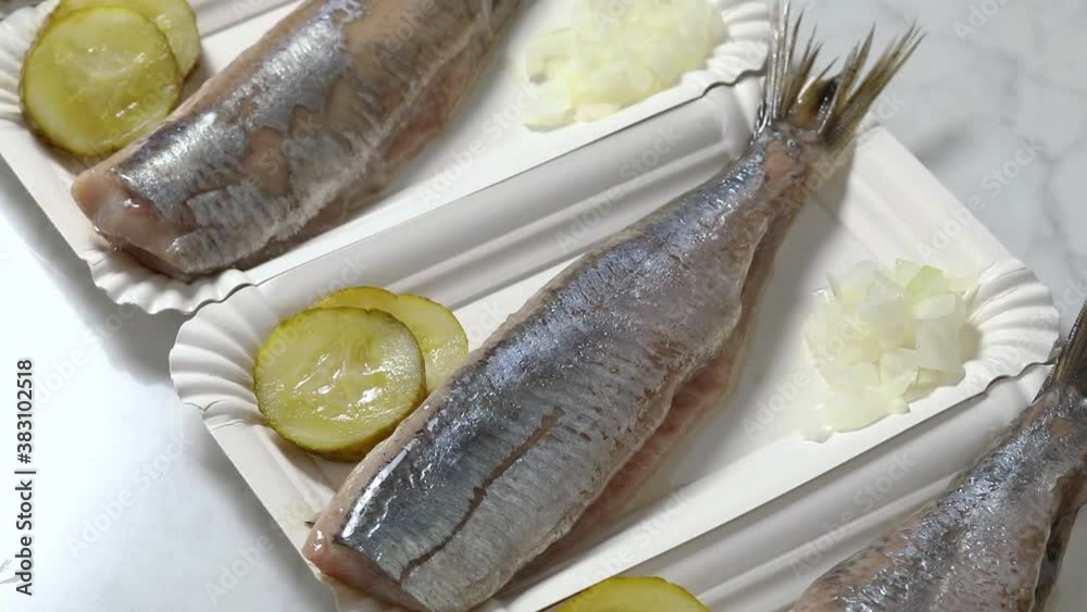 Row of fresh Dutch raw herring on disposible plates close up Row of fresh Dutch raw herring on disposible plates close up