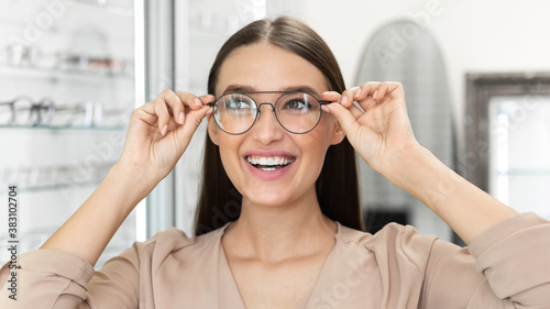 Portrait of beautiful young woman trying on spectacles